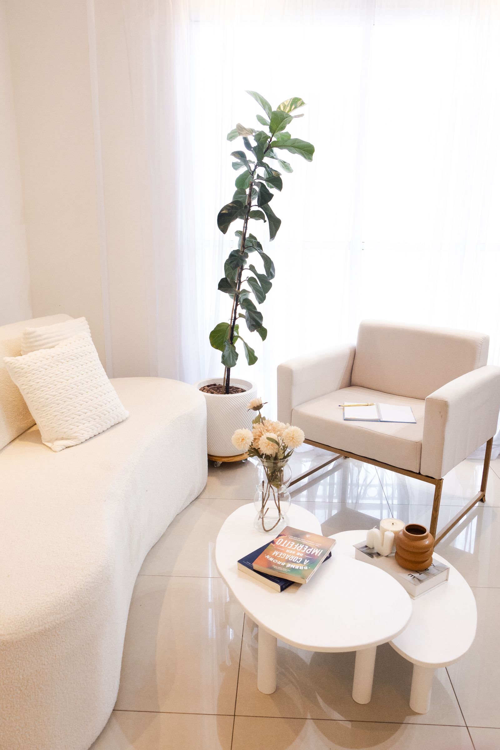 Heller, ruhiger Praxisraum mit weichem Sofa, Sessel und Pflanze in warmem Tageslicht