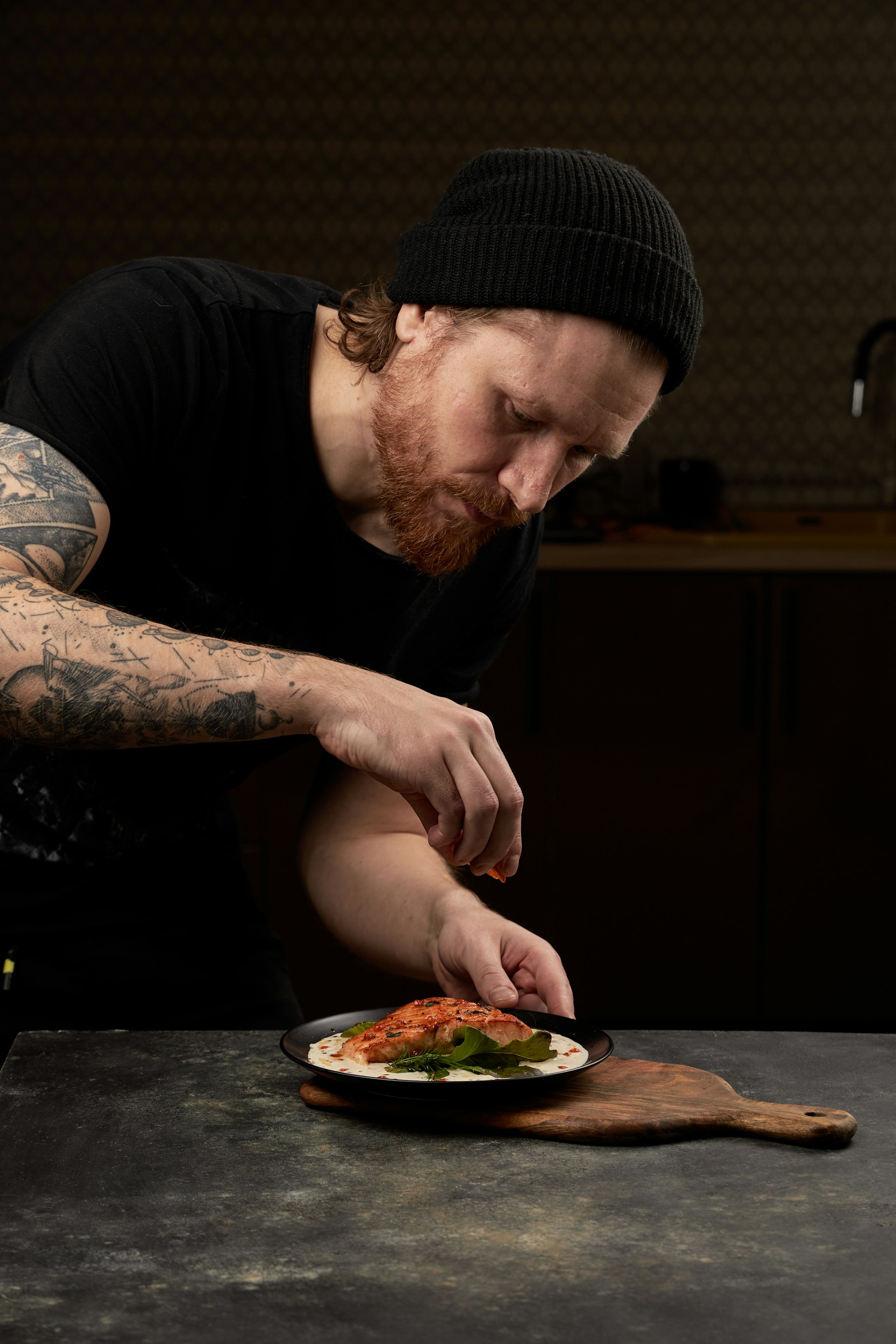 Elias Moreau, Executive Chef at NOIRÉ, plating a dish in the dark kitchen.